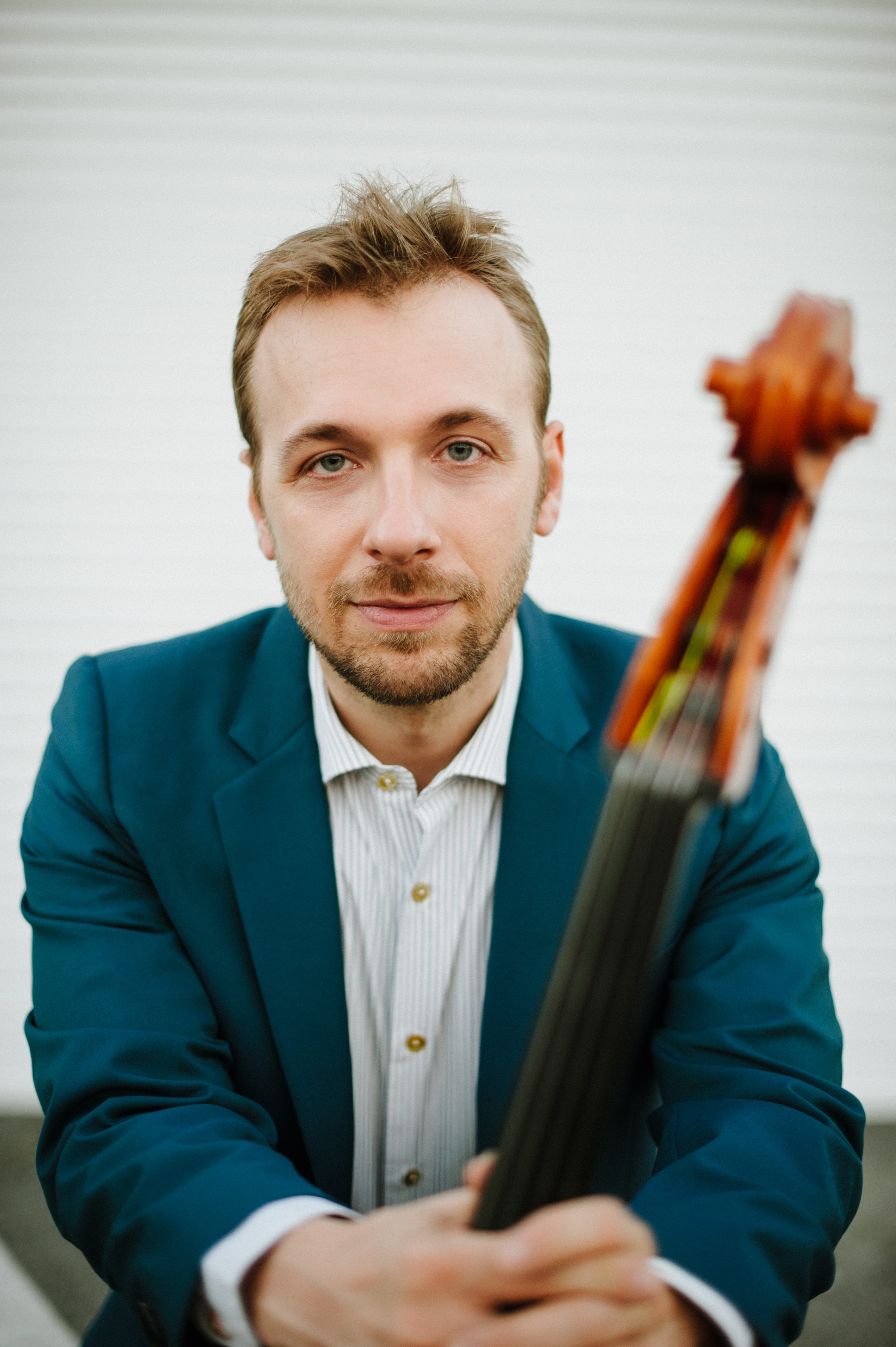 Man holding cello while wearing a blue suit