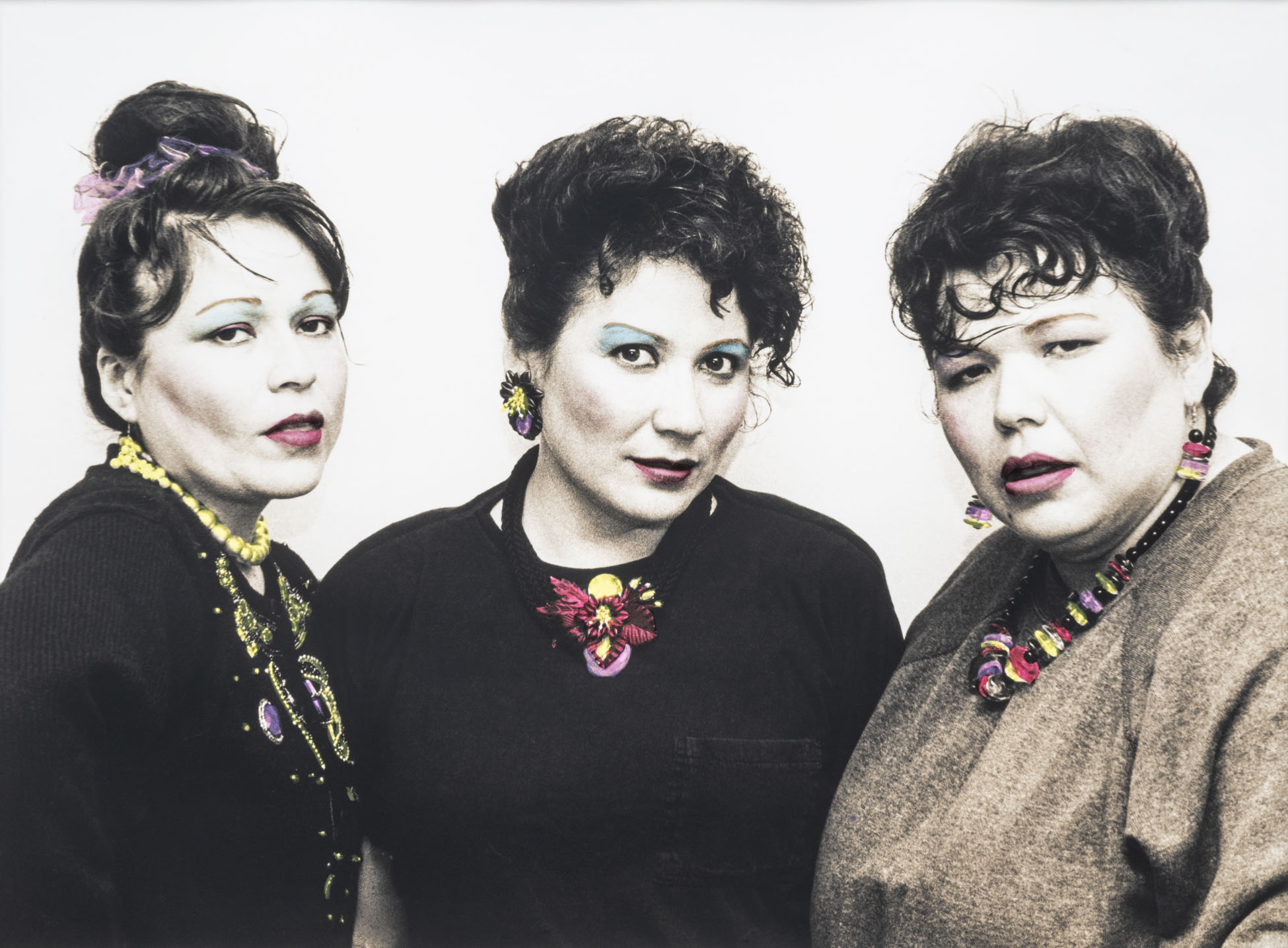 Three women in beehives look at the camera