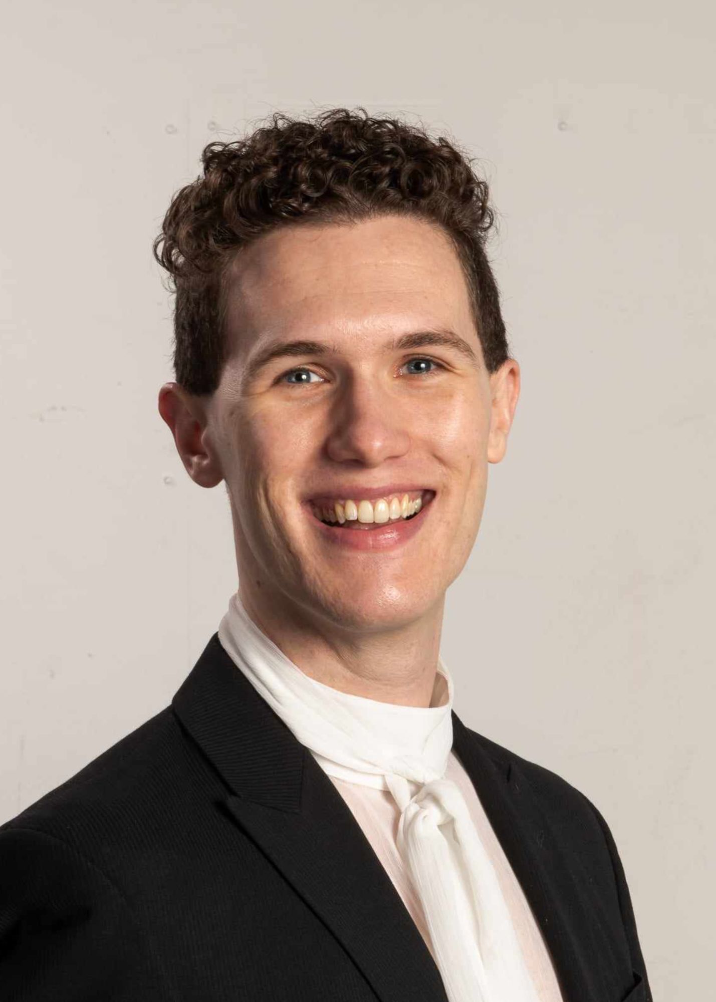 Man in performance attire smiling broadly at camera