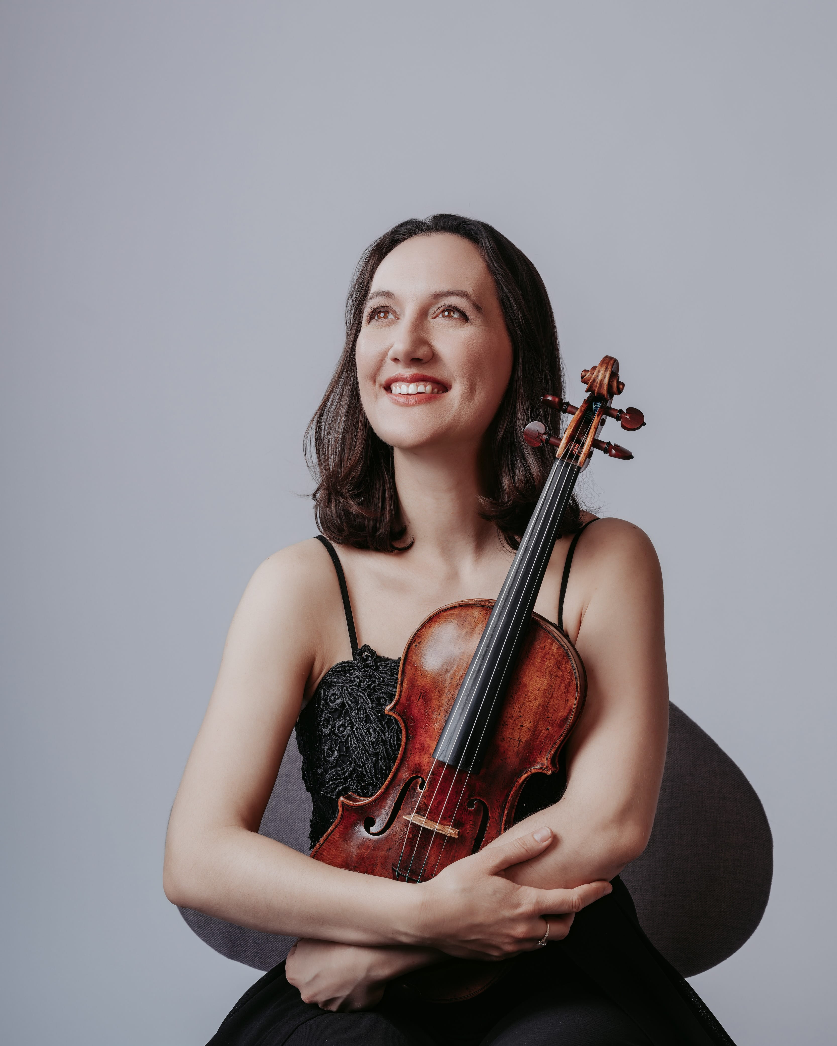 A woman is seated with a violin on her lap