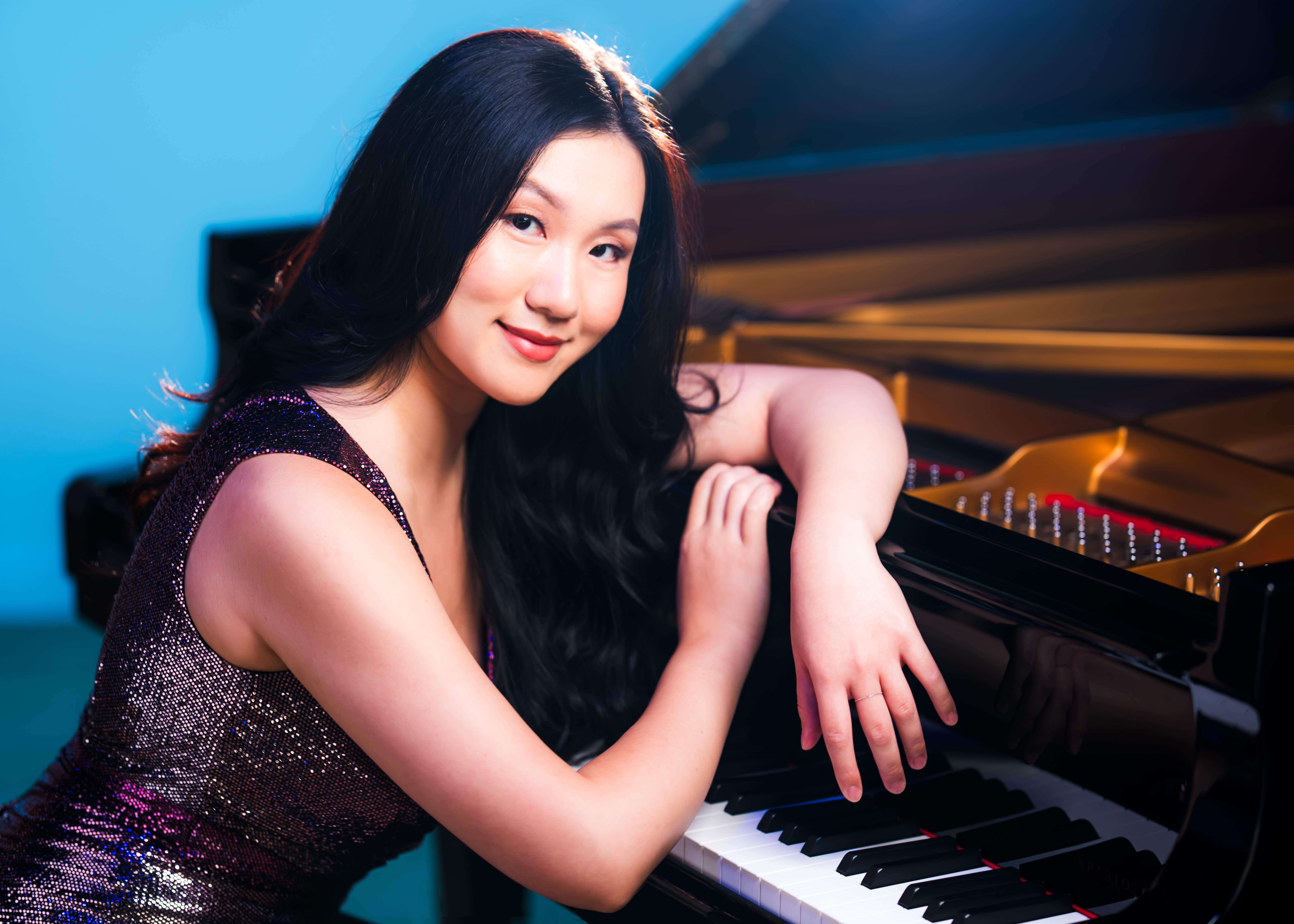 Woman Leaning over piano smiling at camera