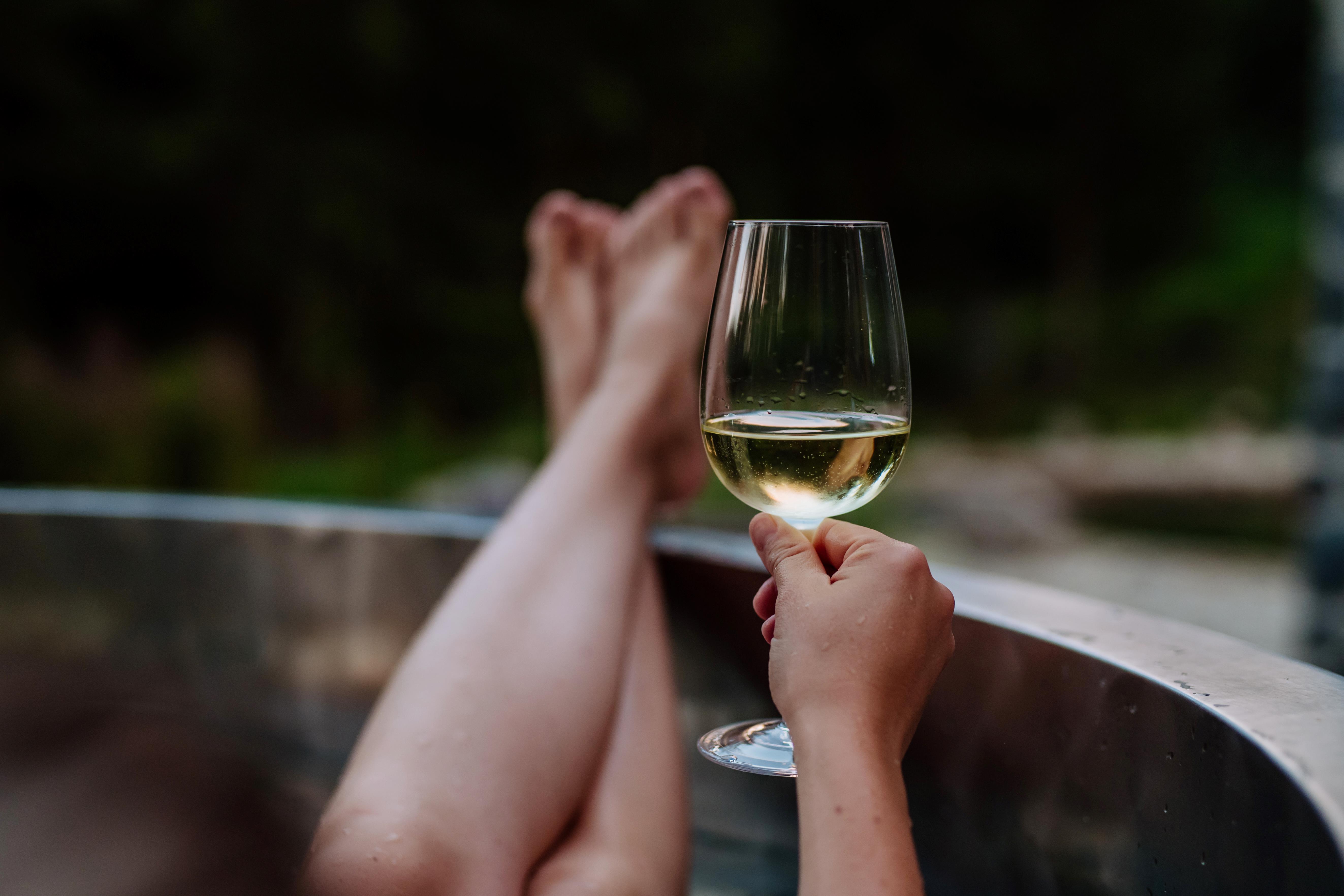 A person sitting in a hot tub with a glass of wine.