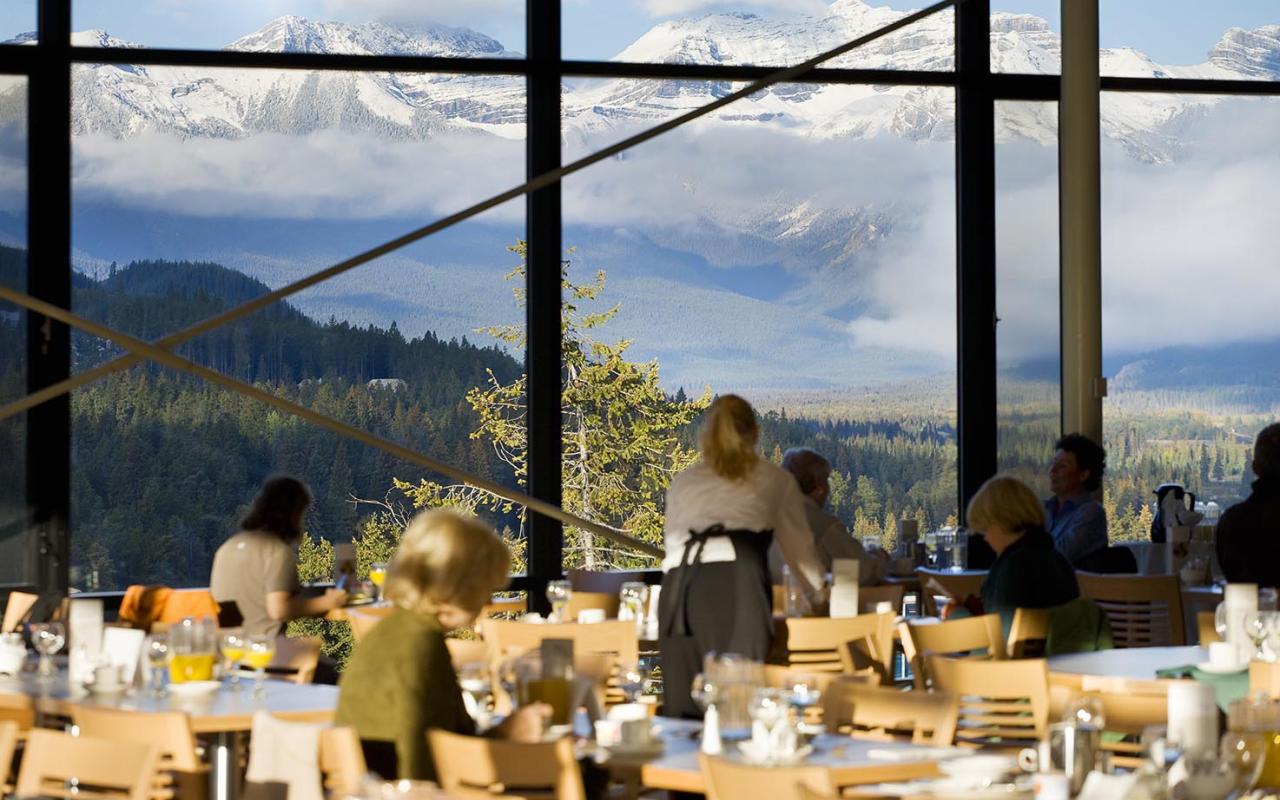 The Vista's dining room with patrons, showing glass windows surrounding the entire space with perfect views of the bow v