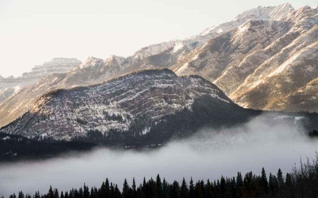 snowy mountain with mist in foreground