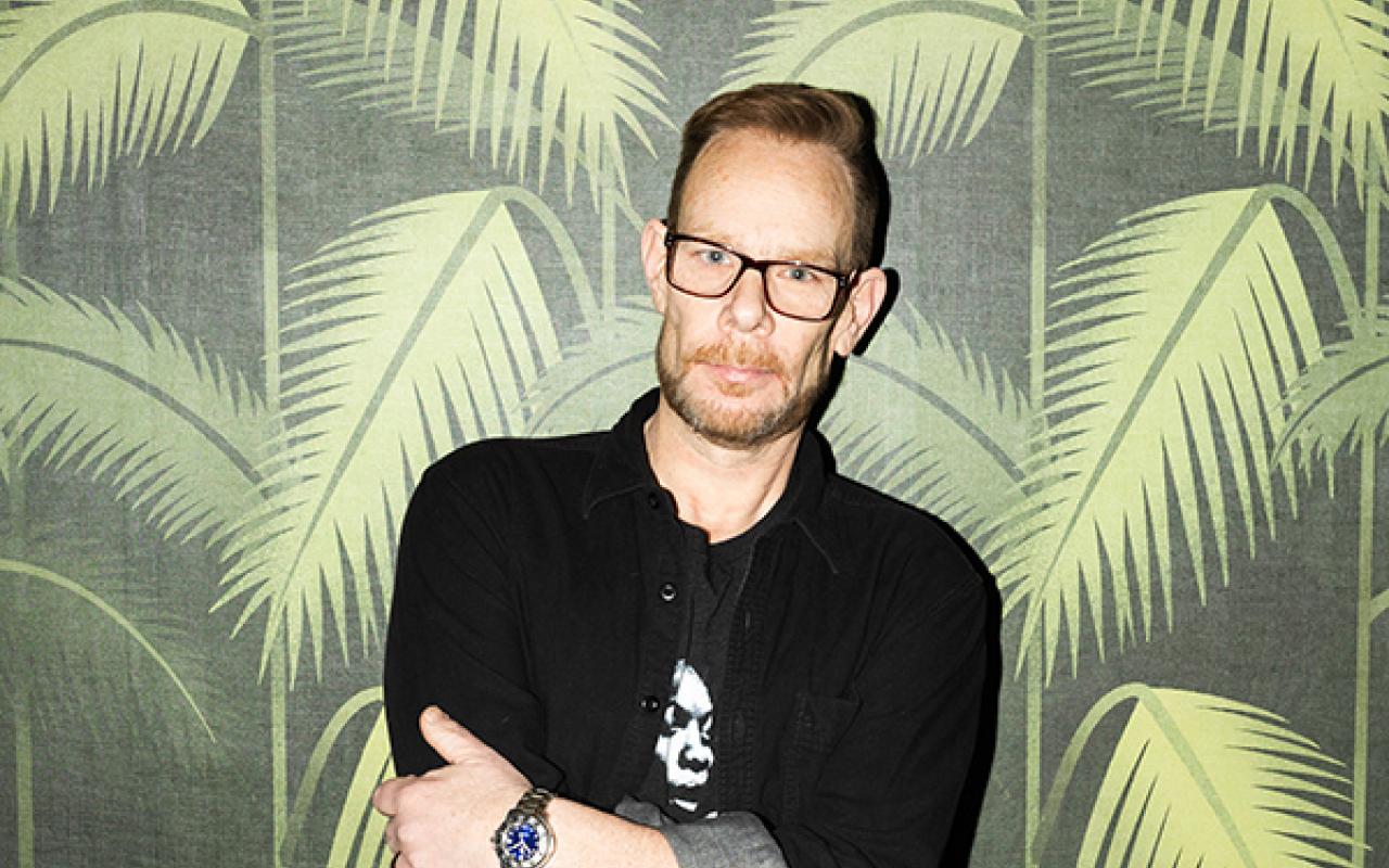 DJ Rob Faust standing against palm tree pattern wall paper