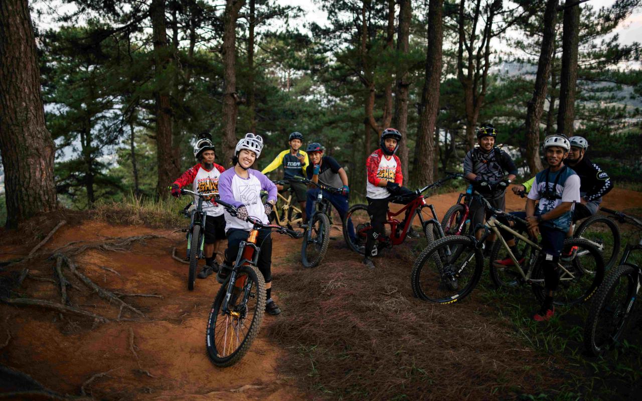 Group of young people posing on their bikes in a forest trail