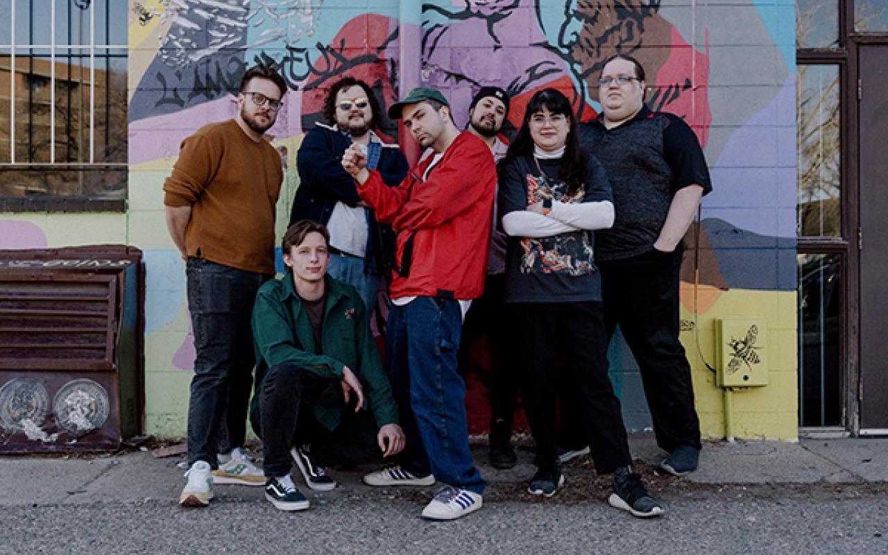 Midnight channel collective standing against a graffitied wall. 