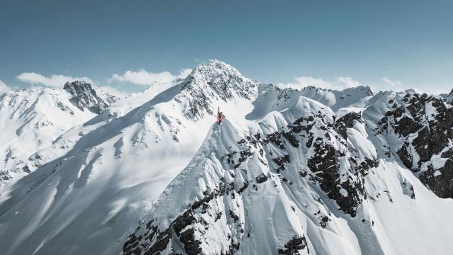 A skier hikes up a high snowy ridge