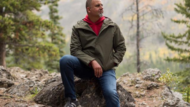 Marcus Youssef sitting on a rock in nature