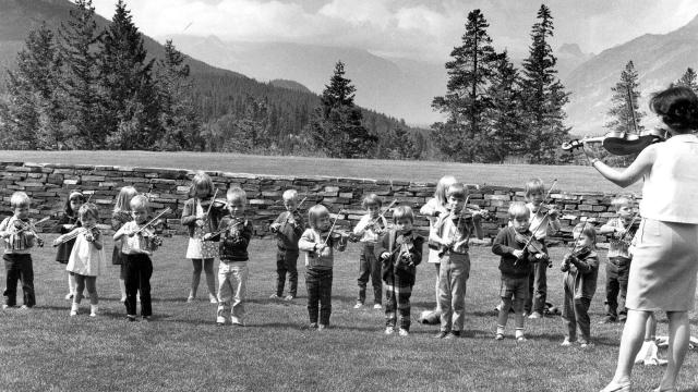 Oike-Wong is pictured here teaching a violin lesson to students on the lawn in front of our Donald Cameron Hall, overloo