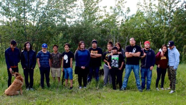 14 members of the Nakoda AV Club stand in a line facing the camera