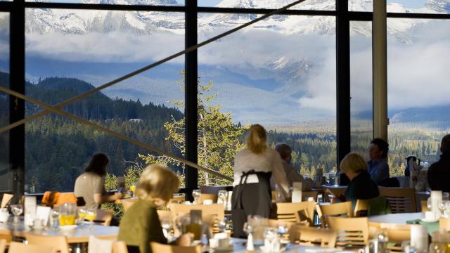 The Vista's dining room with patrons, showing glass windows surrounding the entire space with perfect views of the bow v