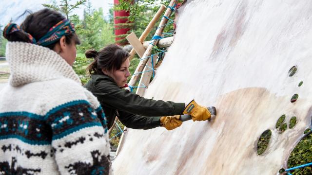 An indigenous artist works on a hide during a residency. 
