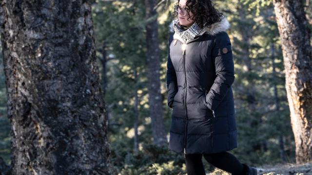 A woman is walking through the woods in winter
