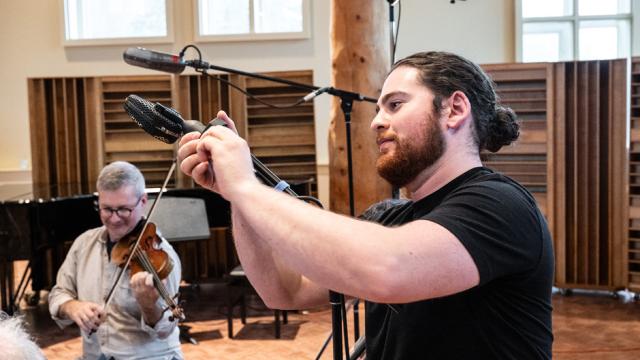 An audio engineer is adjusting a microphone 