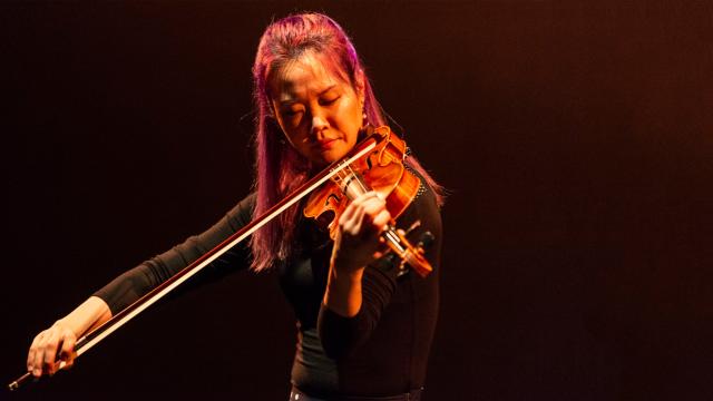 Female Violinist performing on a dark stage. 