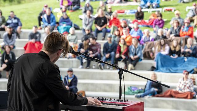 Outdoor setting with a musician on stage in front of a crowd