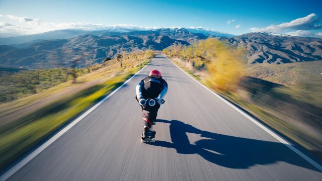 Man on a skate taking speed in a road 