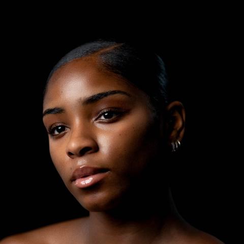 Portrait of woman from shoulders up with head tilted to right but looking directly at camera