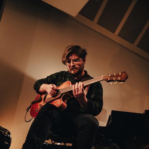 Upward shot of a man playing guitar sitting on a piano bench 