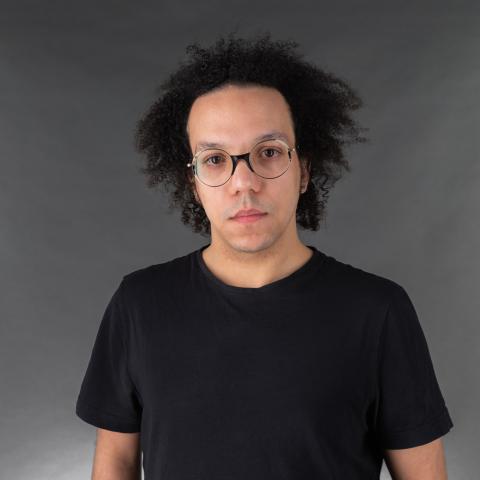 Man wearing a dark t-shirt and glasses staring at the camera