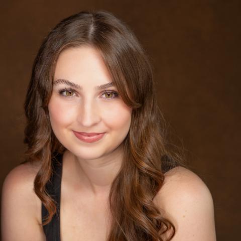 Woman with long blonde wavy hair falling over her shoulders and smiling directly at camera