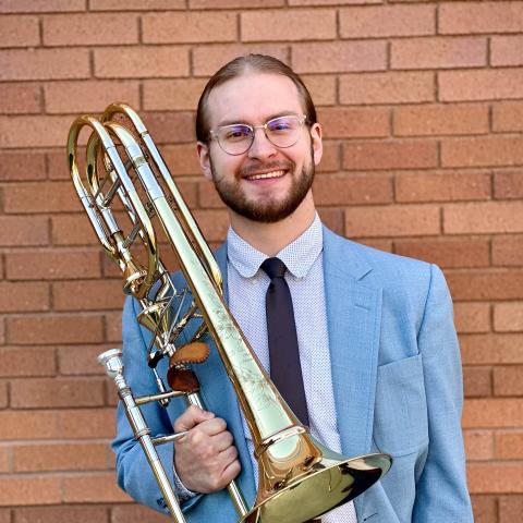 Man in suit holding trombone and smiling at camera
