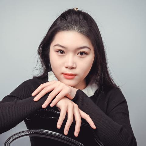 Woman sitting backwards on a chair in a black sweater looking directly at the camera