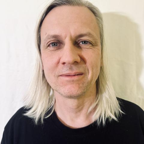 Person with blonde shoulder length hair looking directly at the camera