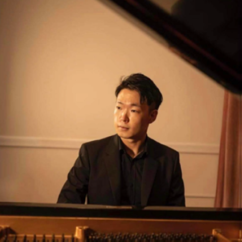 Man sitting behind piano looking off camera