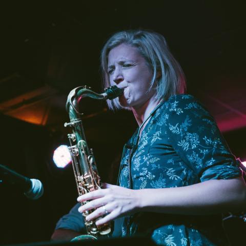 Woman playing saxophone in a performance at the mic