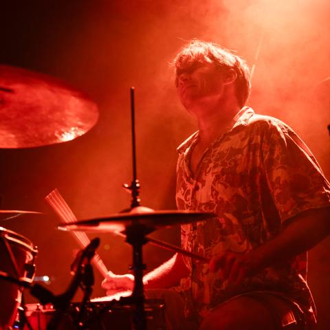 Drummer behind a drum set playing during a performance