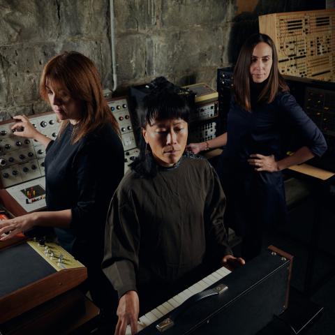 3 people standing in a circle with instruments surrounding them