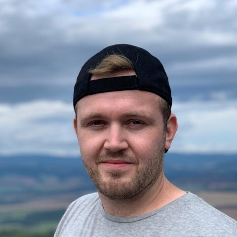 Man in a casual t-shirt and backwards baseball hat on a hill