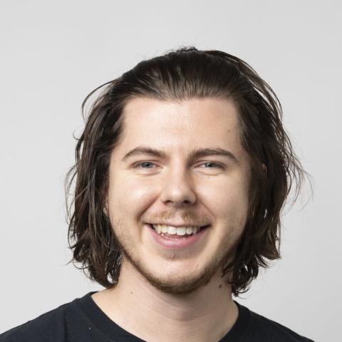 Man with shoulder length hair smiling broadly at camera