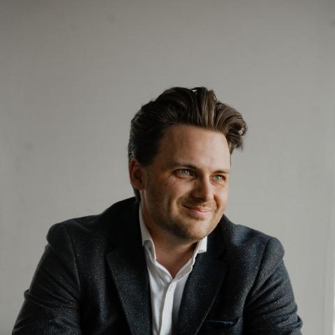 Man smiling off to the side holding clasped hands in lap