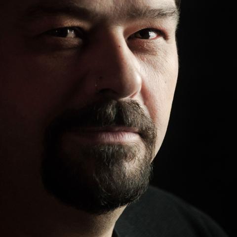 Close up of Michel's face with a small smile and looking directly into the camera