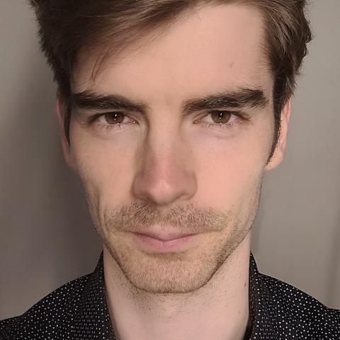 Close up shot of a man with short, voluminous hair looking directly at the camera
