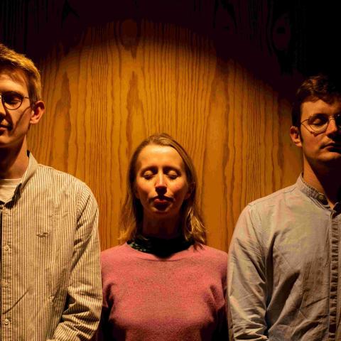 Members of Extended Music Collective standing shoulder to shoulder against a wooden door