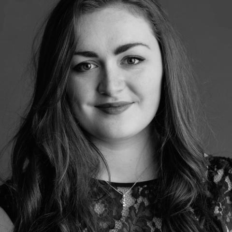 Black and white photo of woman with long curled hair smiling at camera