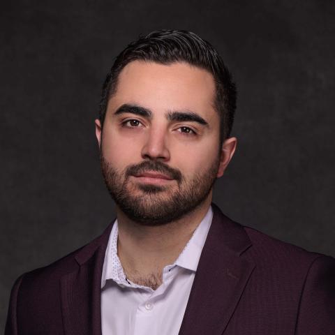 A man with short hair smiling slightly and looking directly at the camera