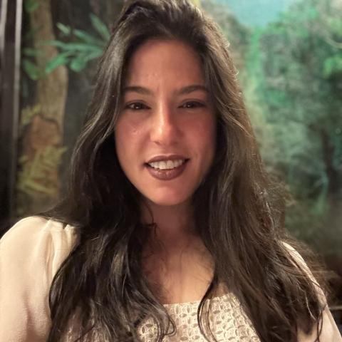 Woman with long flowing dark hair over her shoulders smiling directly at the camera