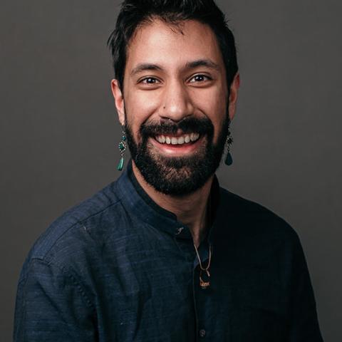 Headshot of Seare as he smiles in front of a charcoal grey backdrop. 