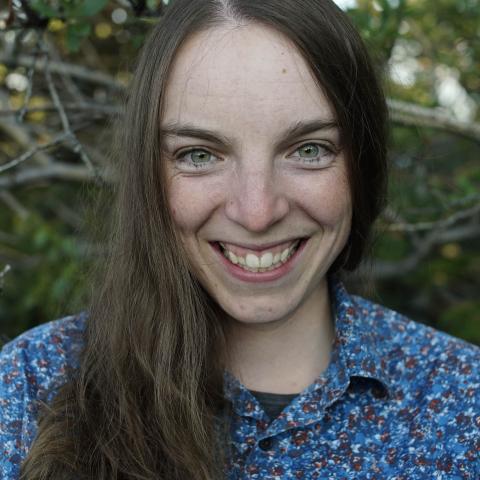 Close up shot of a woman smiling at the camera wearing a patterned shirt