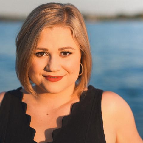 Headshot of person standing in front of water with smile 