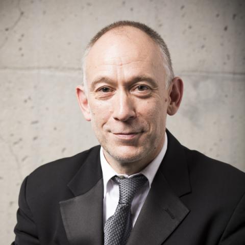 Man smiling lightly at camera wearing suit and tie