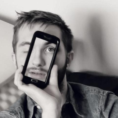 Man holding phone in front of face with the image of his face on the phone screen so that the full face is visible