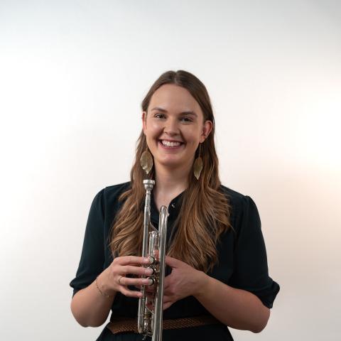 Woman smiling at the camera holding trumpet in front of her