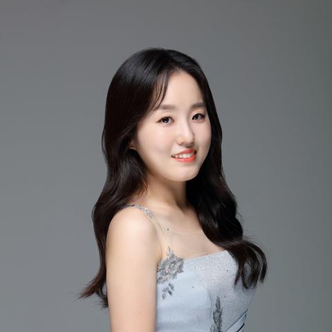 Woman with long dark hair wearing a formal dress smiling at the camera