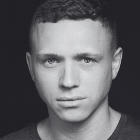Black and white close up headshot of man staring directly into camera